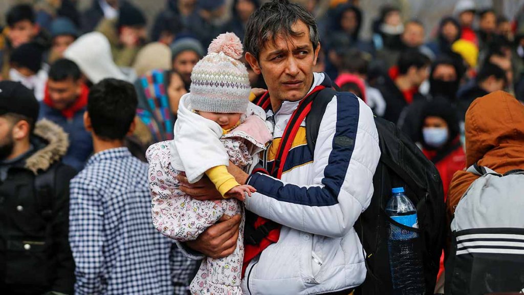 Padre refugiado con su hija en brazo en un campamento improvisado