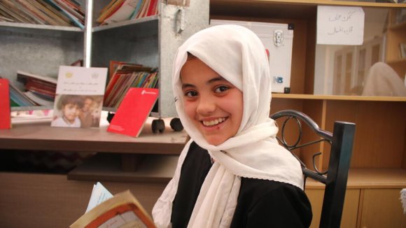 Educación de calidad - Una niña con un libro sonriendo