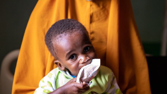Ahmed, 1 año, come pasta de cacahuete en un centro de Save the Children