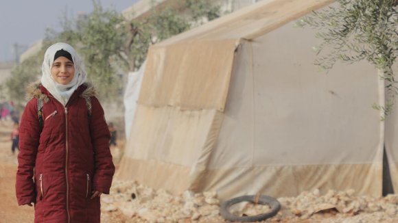 Marah, niña refugiada siria delante de una tienda de un campamento