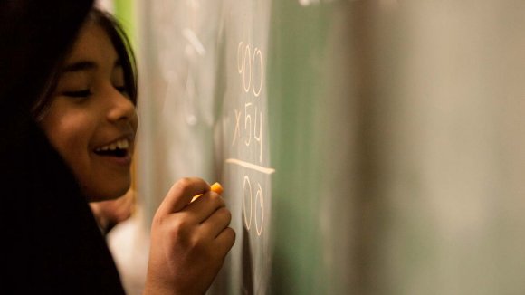 Niña en un colegio Niña en un colegio escribiendo en una pizarra