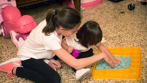 Dos niñas jugando y pintando juntas en el suelo de un piso