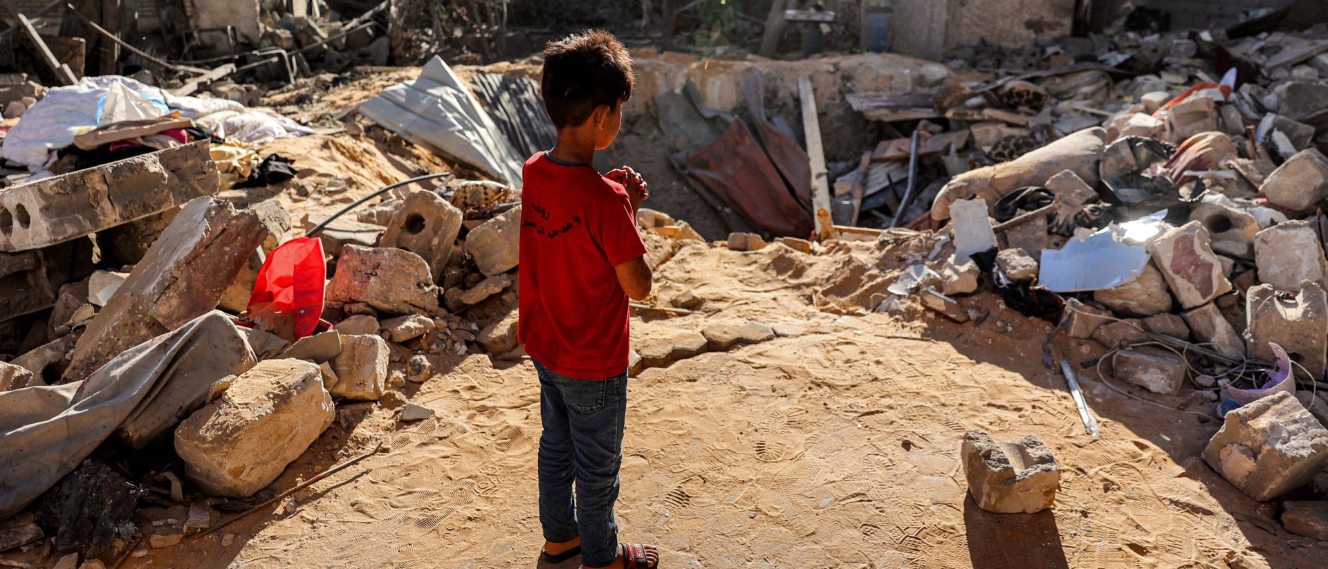Niño en Gaza delante del cráter de una bomba