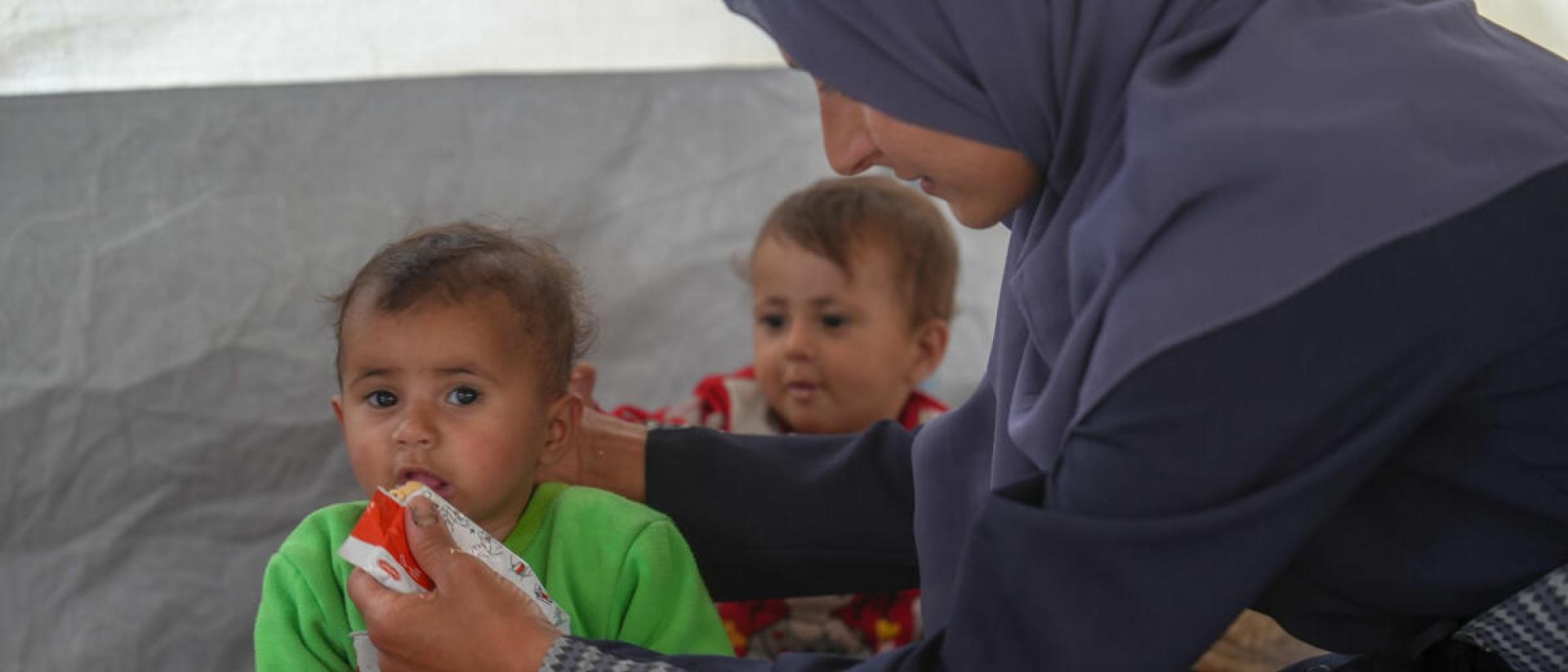 Ahlam (36) alimenta a sus gemelas Tala y Ghadeer (18 meses) con pasta terapeútica en una clínica de Save the Children. Créditos: Save the Children