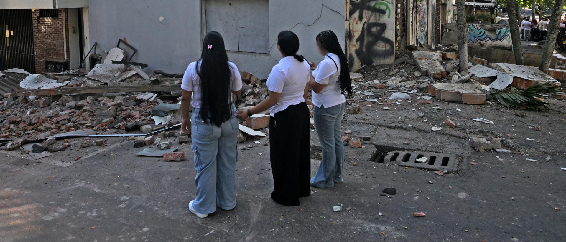 mujeres miran un edificio colapsado