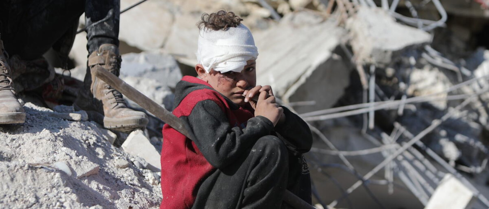 Niño sirio víctima del terremoto junto a su casa destruida