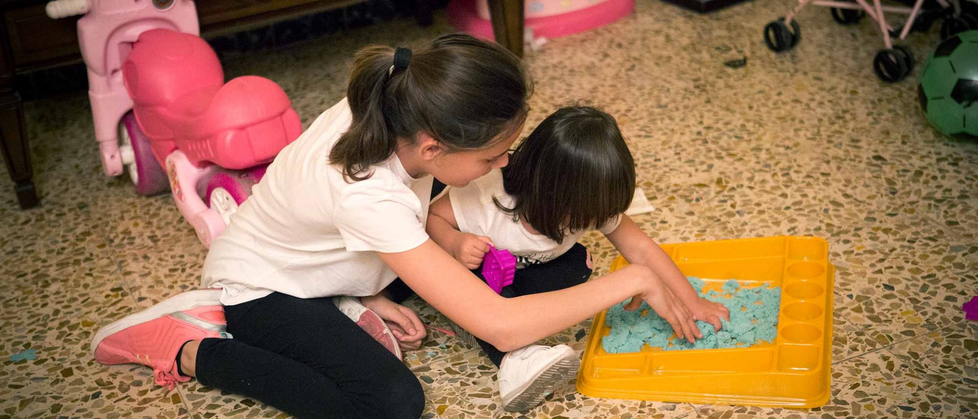 Dos niñas jugando y pintando juntas en el suelo de un piso