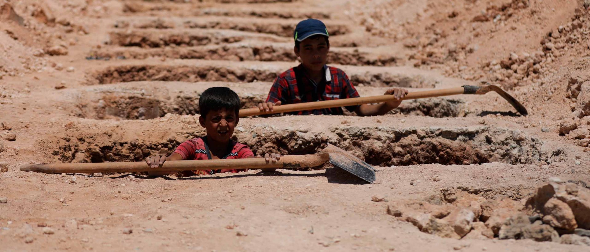 Niños cavando tumbas en Siria, dos hermanos dentro de una tumba Niños cavando tumbas en Siria
