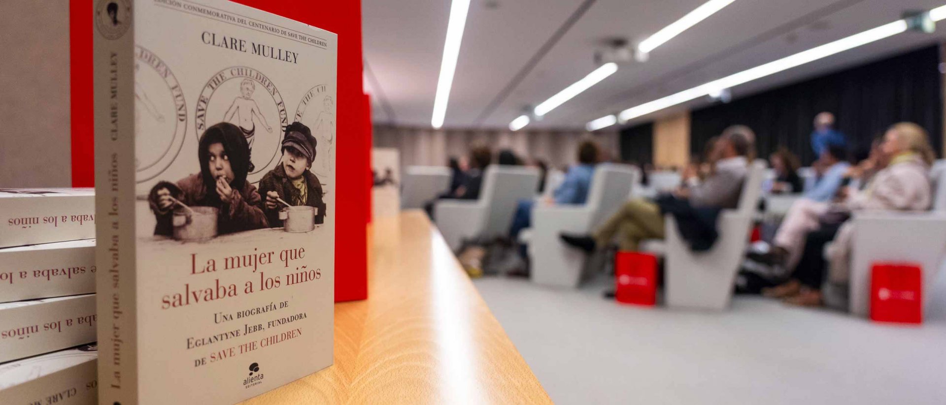 Presentación Biografía Eglantyne Jebb - Portada del libro y sala al fondo Presentación Biografía Eglantyne Jebb