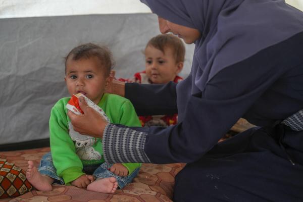 Ahlam (36) alimenta a sus gemelas Tala y Ghadeer (18 meses) con pasta terapeútica en una clínica de Save the Children. Créditos: Save the Children