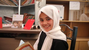 Educación de calidad - Una niña con un libro sonriendo