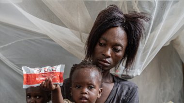 Celine, 13 meses, sentada en el regazo de su madre, Anne Marie, sosteniendo un paquete de Plumpynut. Superviventes del hambre