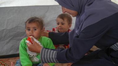Ahlam (36) alimenta a sus gemelas Tala y Ghadeer (18 meses) con pasta terapeútica en una clínica de Save the Children. Créditos: Save the Children