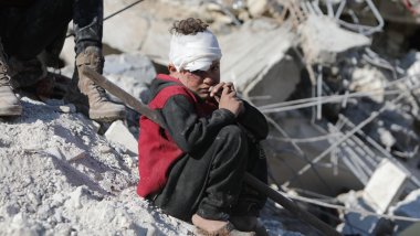 Niño sirio víctima del terremoto junto a su casa destruida