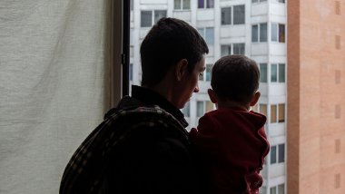 informe-vivienda_padre-mirando-a-la-ventana-con-hijo-en-sus-brazos