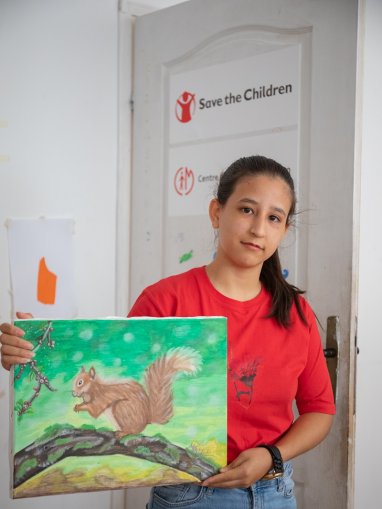 Selma* con un dibujo hecho por ella en el espacio amigable para niñas y niños
